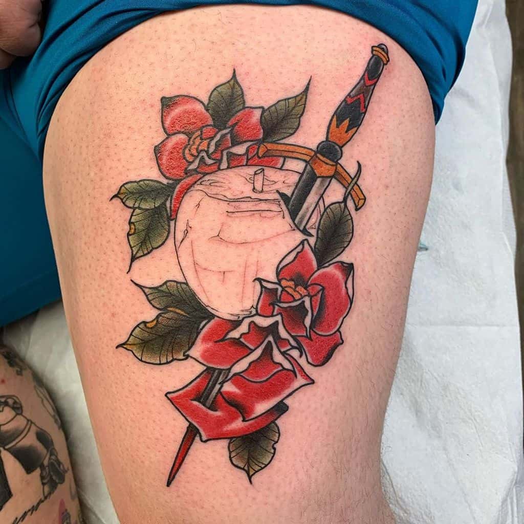 Tattoo of an apple with a sword through it, surrounded by red roses and green leaves