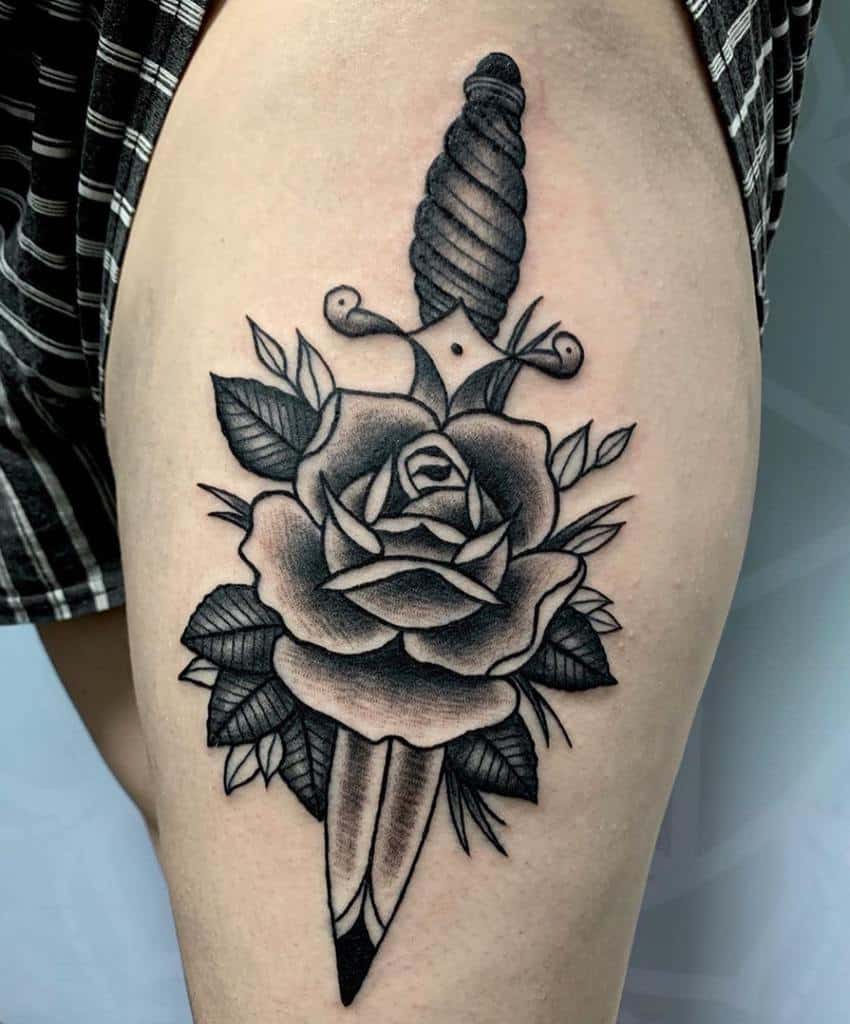 Traditional tattoo of a dagger through a rose on a thigh
