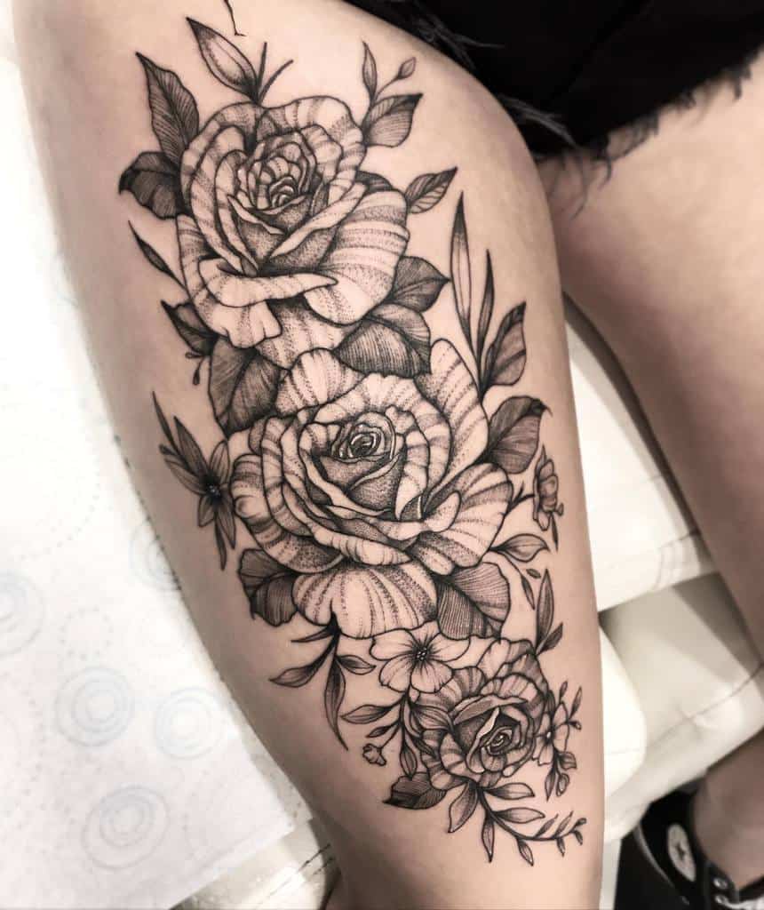 This intricate thigh tattoo features layered roses with detailed line work and shading, accompanied by delicate leaves and smaller floral elements, creating a balanced and elegant design