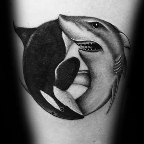 Black and gray tattoo on the forearm featuring an orca and a shark in a yin-yang design, symbolizing the balance between the two powerful marine creatures.