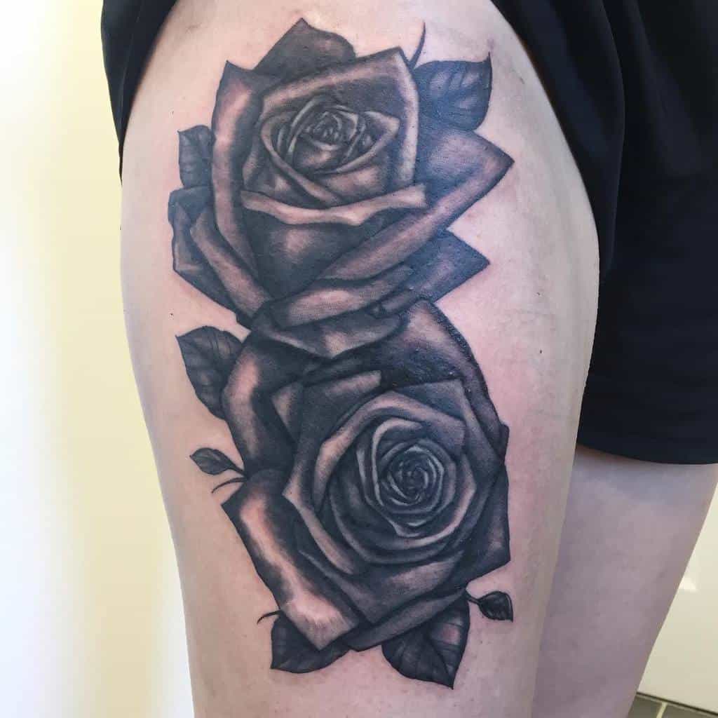Tattoo of two large, detailed roses on a thigh