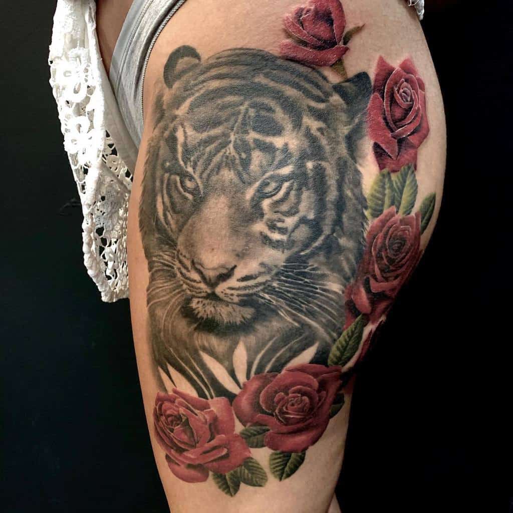 Tattoo of a tiger surrounded by red roses on an upper thigh