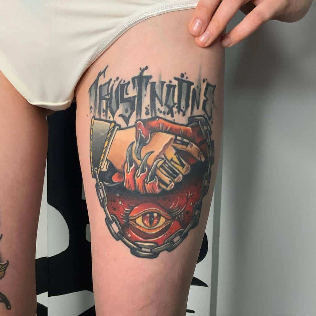 Colorful thigh tattoo featuring a chained handshake with skeletal fingers, an eye symbol, and bold 'Trust No One' lettering
