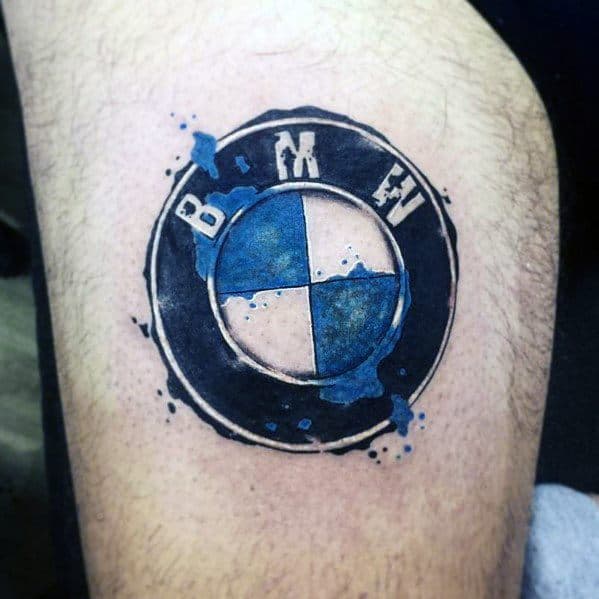 Bold BMW logo tattoo on leg, featuring a worn-out effect with blue paint splashes for a rugged and artistic automotive design.