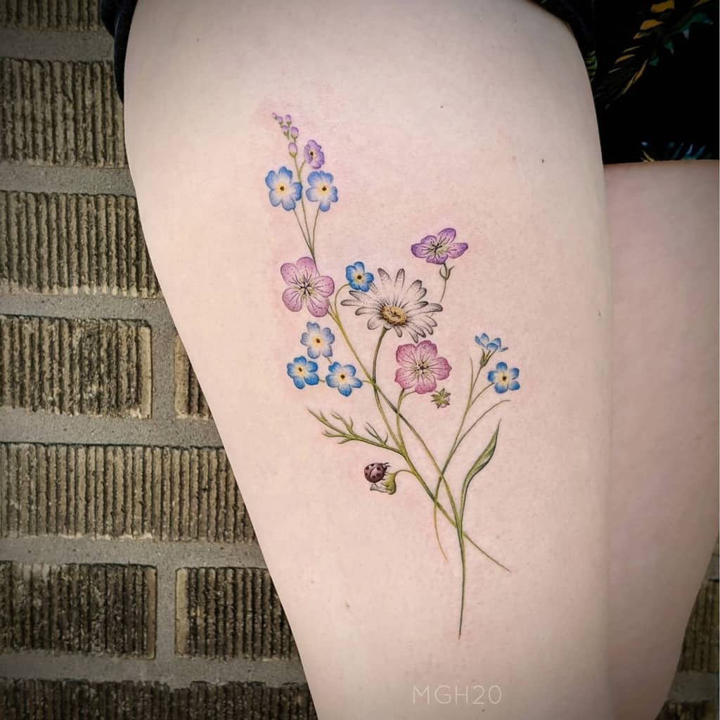 Floral tattoo on thigh with pink, purple, and blue flowers and green stems