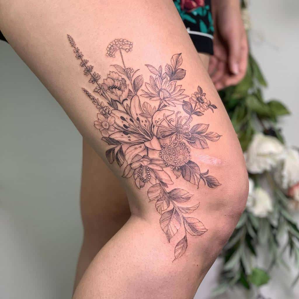 Floral tattoo on a thigh, featuring detailed leaves and flowers