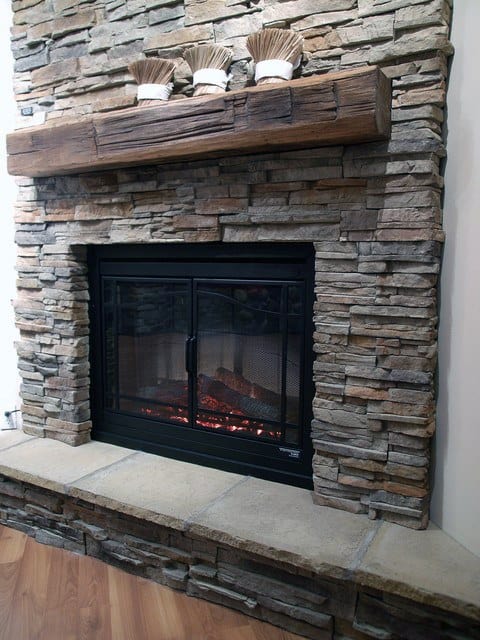 A cozy stone fireplace with a wooden mantel and warm rustic charm.