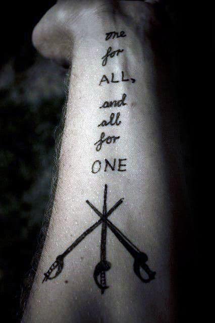 Tattoo on an arm reading "one for ALL, and all for ONE" with crossed swords beneath
