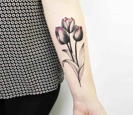 Arm tattoo of three black and pink tulips with leaves