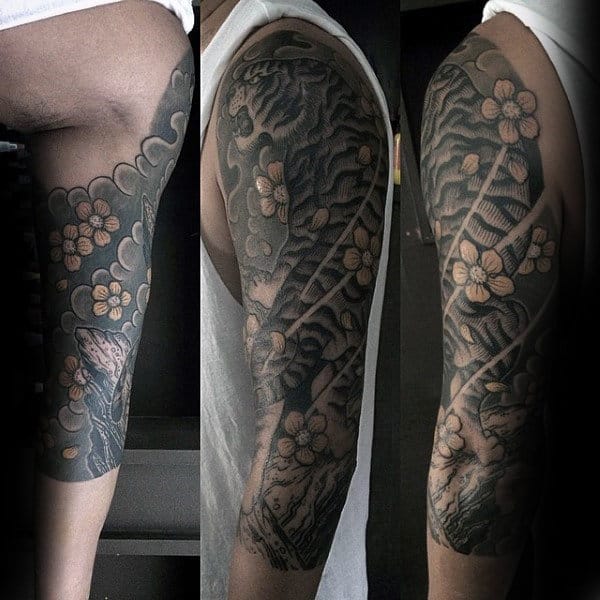 Black and grey half-sleeve tattoo featuring a fierce tiger, flowing wind patterns, and cherry blossoms for a bold yet elegant Japanese design