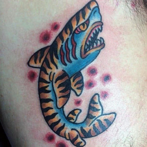 Fierce tiger shark tattoo with bold black stripes, blue body, red gills, and a roaring mouth, surrounded by red shaded dots.