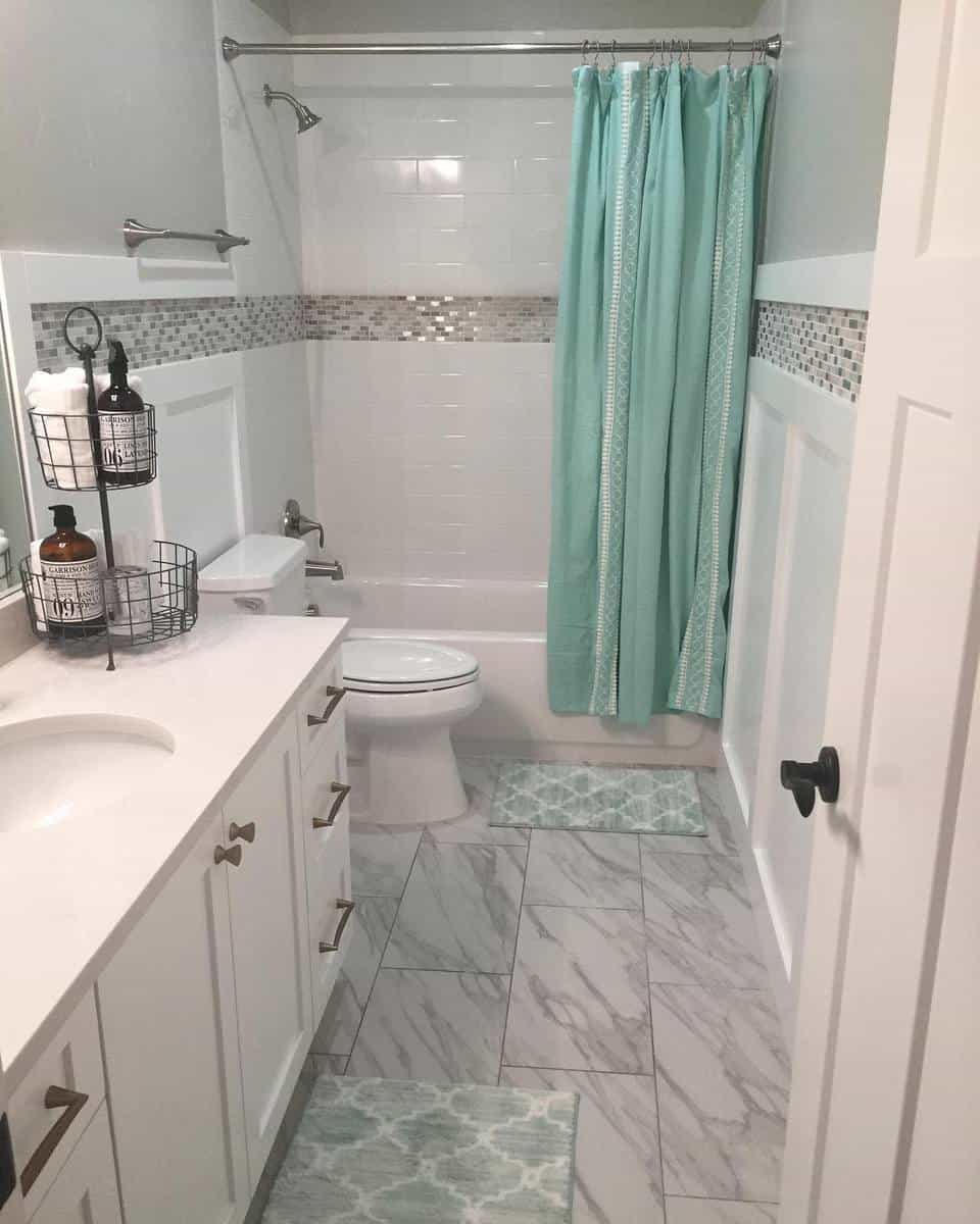 Modern bathroom with marble tile floor, turquoise shower curtain, and white vanity.