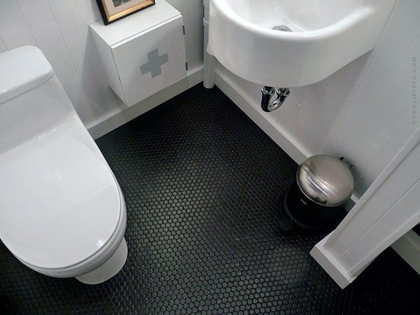 Small bathroom with black hexagon floor tiles, white fixtures, and wall-mounted sink.