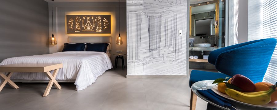 Modern luxury bedroom with artistic wall design, blue accent chair, and pendant lighting.