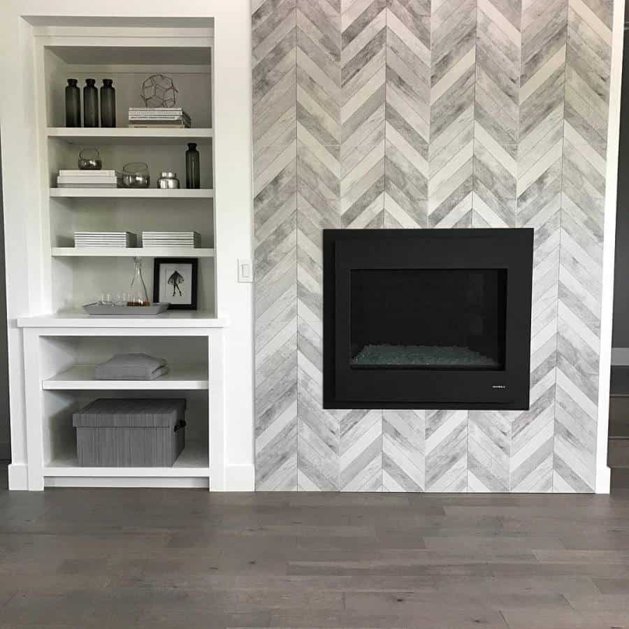 Modern fireplace with herringbone tile pattern, creating an accent wall flanked by white shelves on a wooden floor