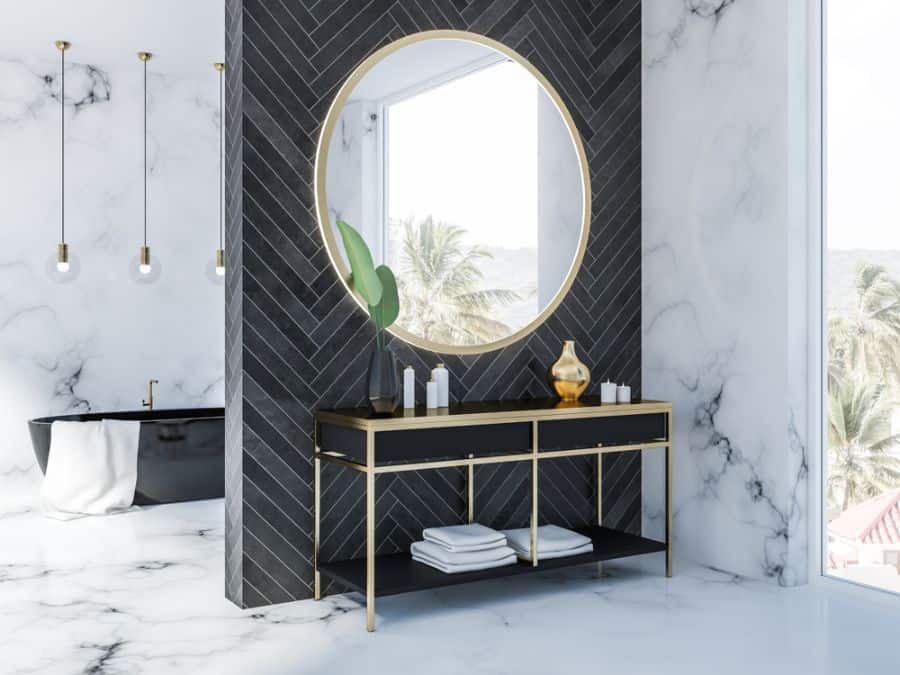 Elegant bathroom with an accent wall, large round mirror, black vanity, marble floor, and tropical view