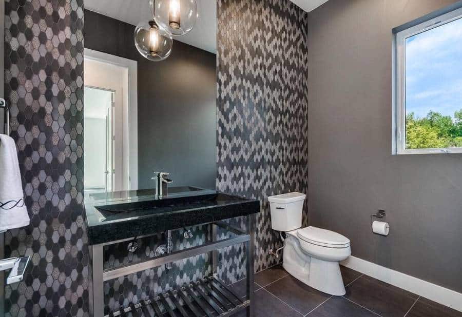 Modern bathroom with dark patterned accent wall, black countertop, and a small window