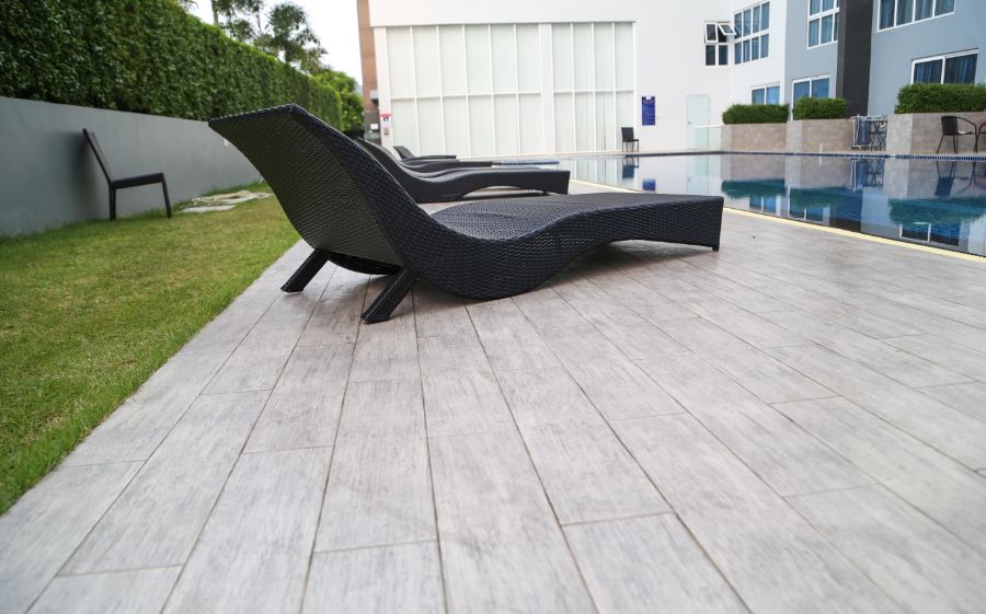 faux wood pool deck with wicker sun loungers