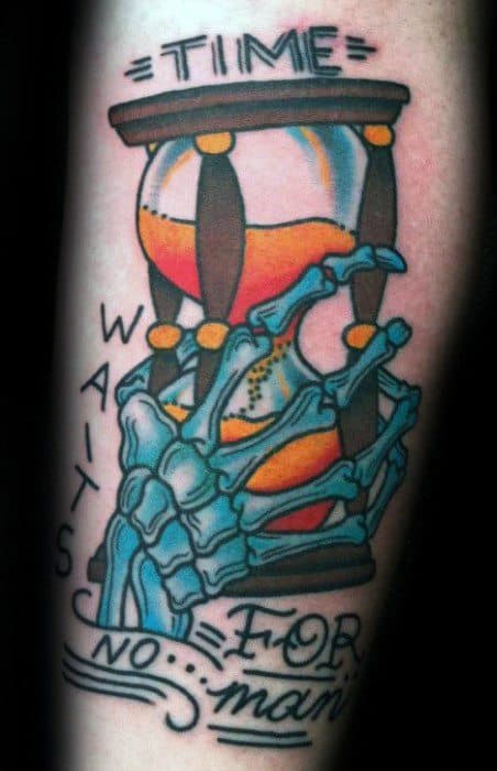 Colorful tattoo of a skeleton hand holding an hourglass with orange sand and stylized text reading Time Waits for No Man.