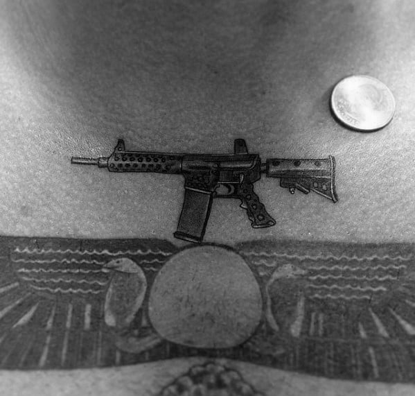Small and detailed black and grey AR-15 tattoo on the chest, positioned near the collarbone, symbolizing strength, precision, and firearm appreciation.