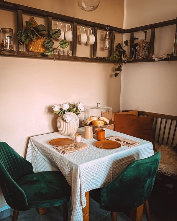 Cozy boho dining nook with a small table, velvet chairs, and vintage decor.
