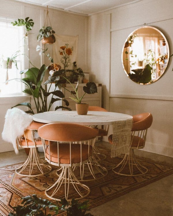 Boho dining room with vintage-style chairs, plants, and soft, neutral tones.