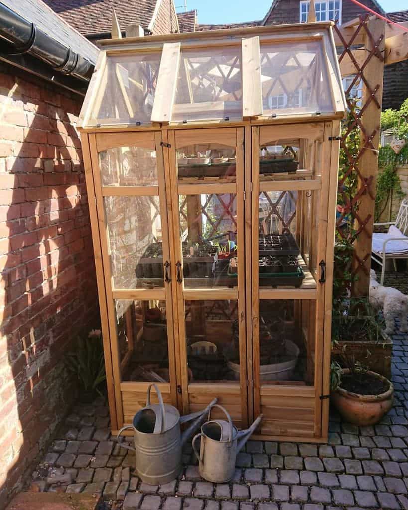 tiny wood greenhouse backyard vintage watering cans