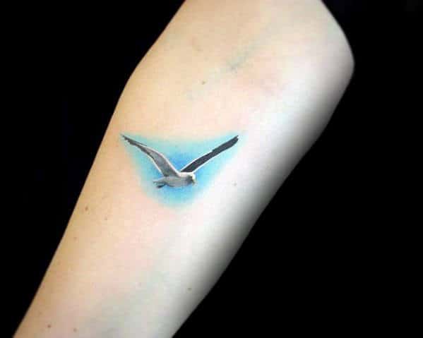 Tiny Mens Detailed Flying Seagull With Blue Sky Background Tattoo Inspiration On Arm
