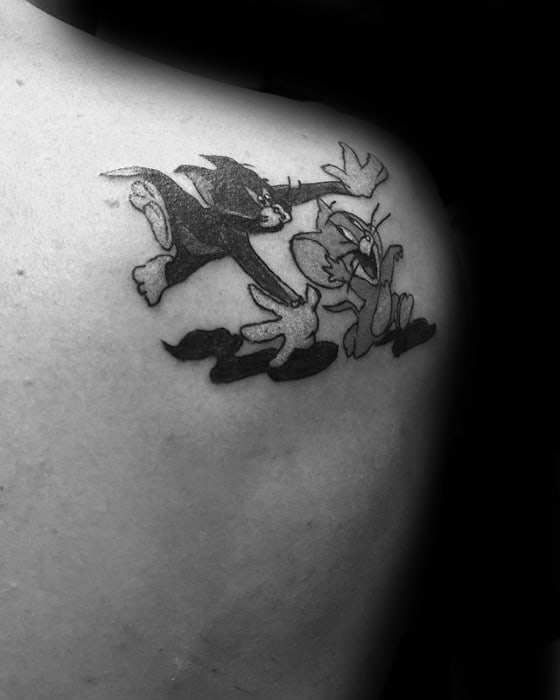 Black and grey shoulder tattoo of Tom chasing Jerry mid-air, capturing their classic cartoon motion with expressive detail.