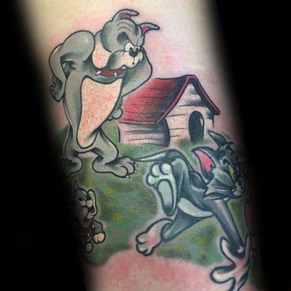 Colorful tattoo of Tom running from Spike and his pup in front of a doghouse, capturing a classic backyard chase scene.