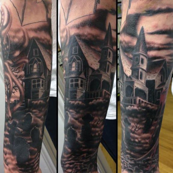 Tattoo of a spooky house with tower, dark clouds, eerie details, and haunted graveyard