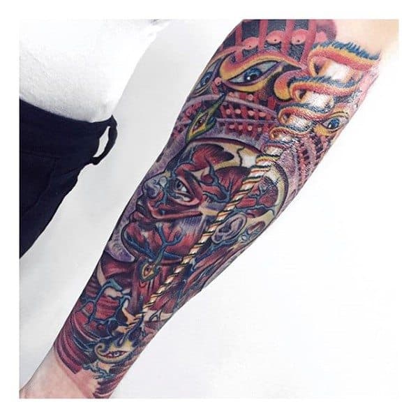 Colorful Tool-inspired forearm tattoo with surreal faces, layered eyes, and abstract organic shapes in a psychedelic, complex composition.