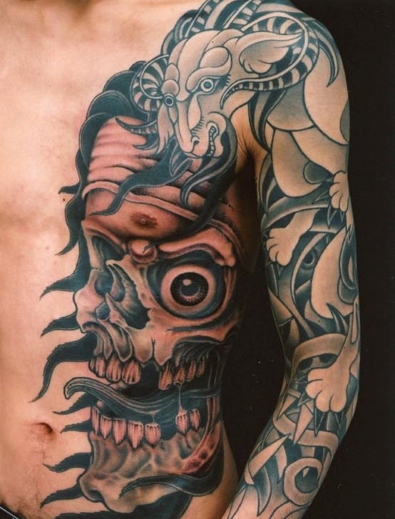 Tattoo of a detailed skull and intricate patterns on a person's chest and arm