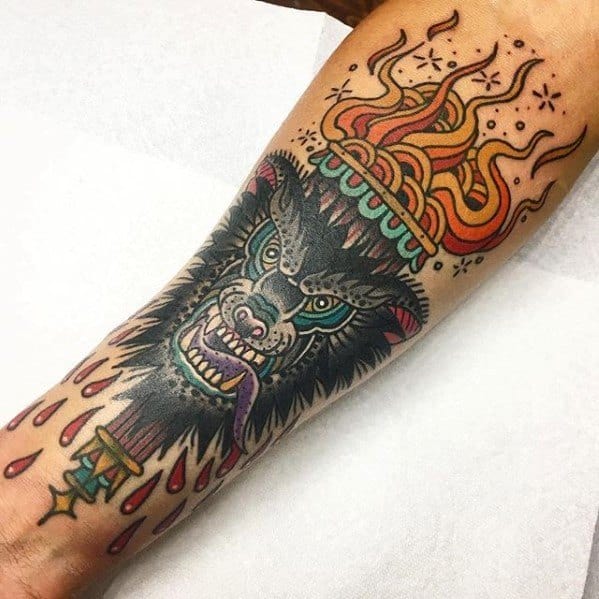 Torch tattoo with a fierce black wolf head, colorful flames above a jeweled crown, and red droplets trailing from the handle.