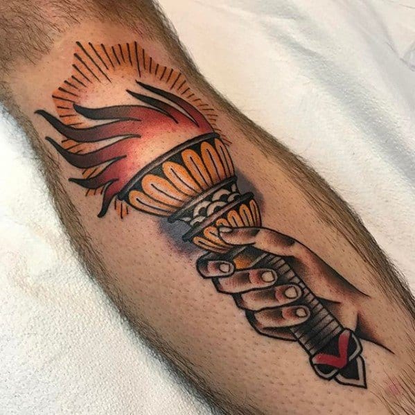 Traditional torch tattoo showing a hand holding a lit flame, with bold black and red accents and a small heart detail on the wrist.