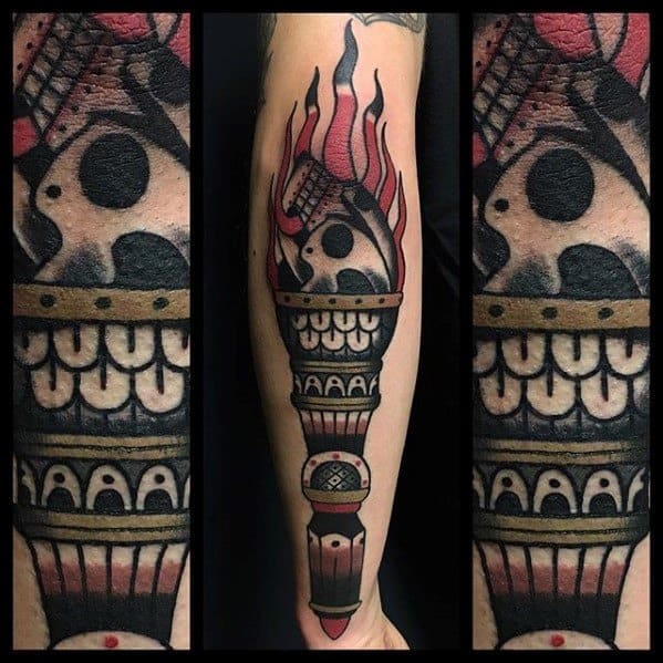 Traditional torch tattoo with bold red flames, a skull inside the flame, and ornamental patterns wrapping around the handle.