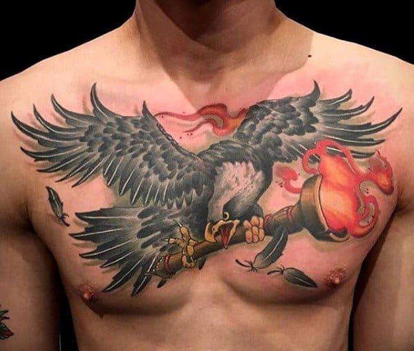 Bold chest tattoo of an eagle clutching a flaming torch in its talons, with vibrant red flames and detailed feather shading.