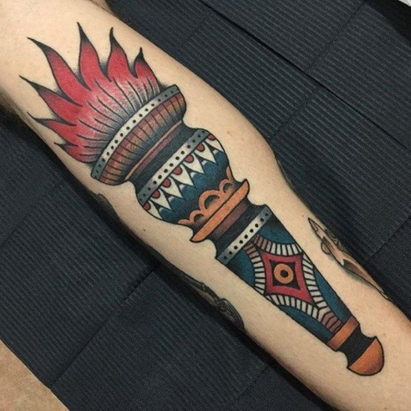 Colorful neo-traditional torch tattoo with bold red flames and a handle decorated in vibrant blue, red, and geometric tribal patterns.