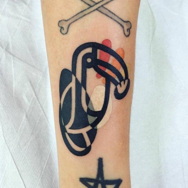Minimalist toucan tattoo with bold black lines and abstract shapes, accented by soft red, orange, and beige color blocks on the forearm.