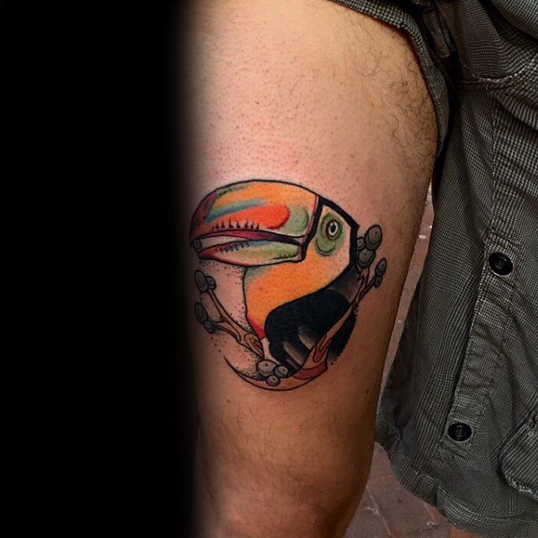 Bold and colorful toucan tattoo on the thigh with an oversized beak and curled toes, combining cartoonish charm with vibrant realism.