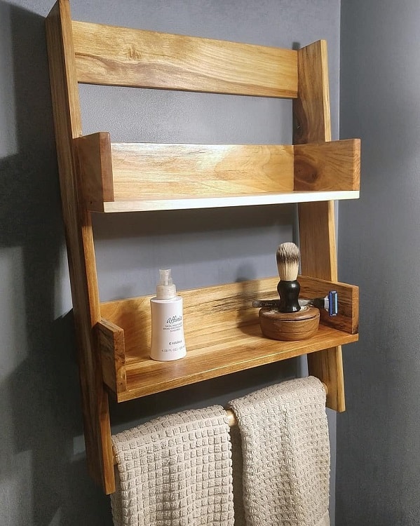 Wooden bathroom shelf with towel holder and shaving accessories.