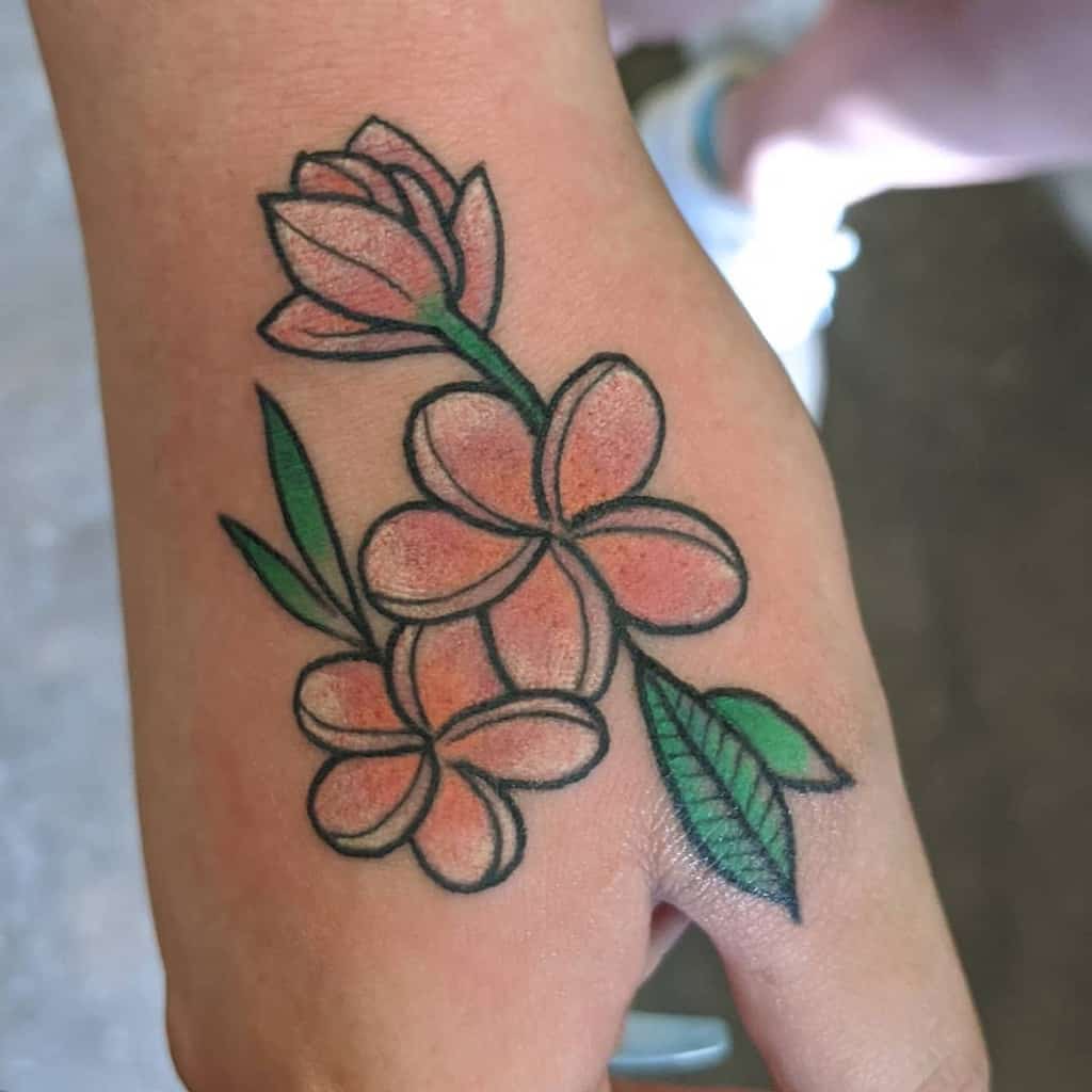 Tattoo of orange and green plumeria flowers on a hand