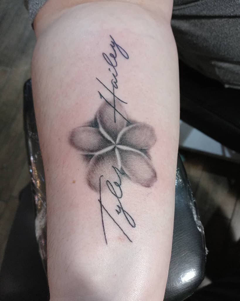 Elegant black and gray Plumeria tattoo with shading details, featuring names 'Tyler' and 'Hailey' in cursive lettering, creating a sentimental and timeless design