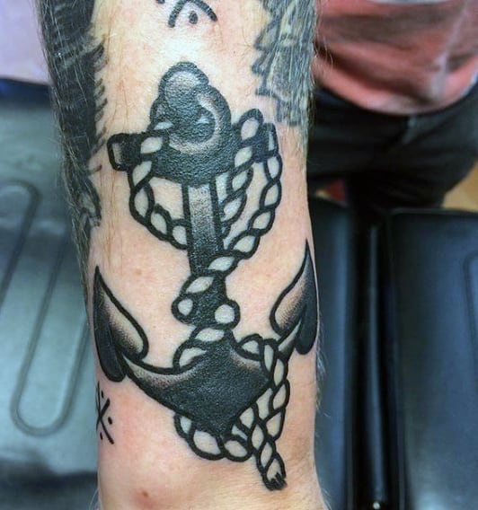 Tattoo of an anchor with a rope design on an arm