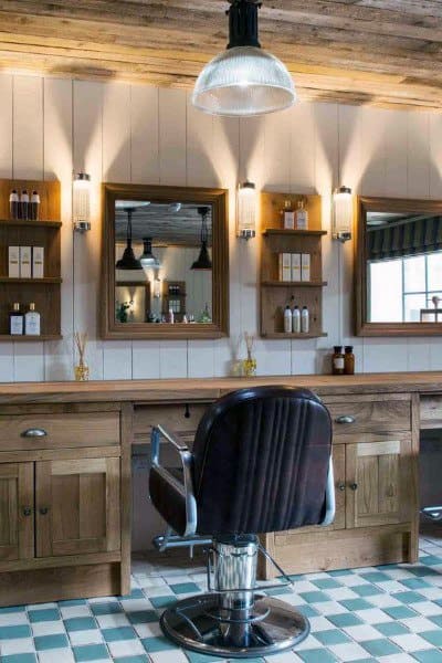 Farmhouse-style barbershop with wooden counters, tiled floor, and vintage lighting fixtures.