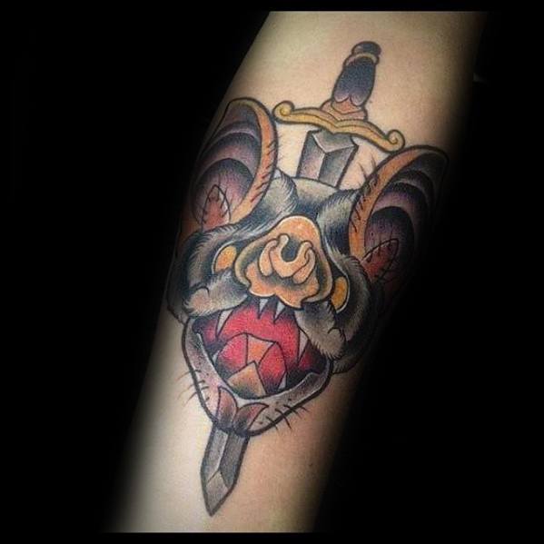 Traditional bat head tattoo with an open mouth and sharp teeth, pierced by a sword, using warm tones and bold outlines.