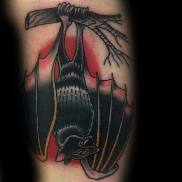 Traditional bat tattoo hanging upside down from a branch with bold black shading, orange accents, and a red background glow.
