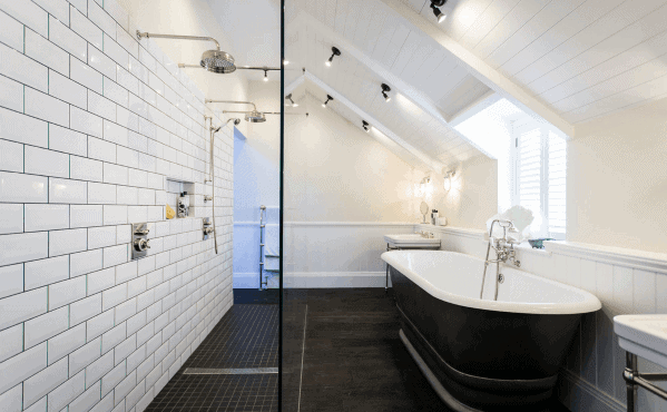 Spacious bathroom with a shower featuring classic white subway tiles, dual showerheads, and a freestanding bathtub, complemented by modern recessed ceiling lighting
