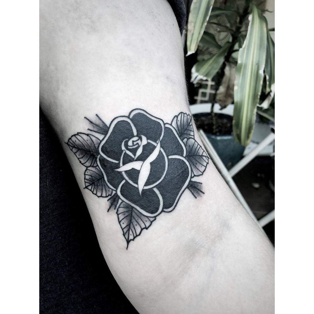 Black and white rose tattoo with leaves on upper arm
