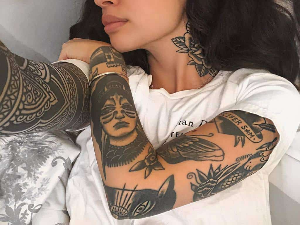 Full sleeve tattoo featuring traditional blackwork designs, including geometric patterns, a woman's face, animals, and floral elements